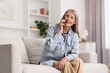 © New Africa - Senior woman talking on phone at home