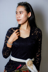 portrait of an Indonesian woman wearing a black kebaya in the studio with a disheveled pose isolated white background