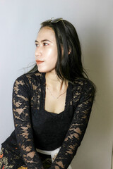 portrait of an Indonesian woman wearing a black kebaya in the studio with a disheveled pose isolated white background