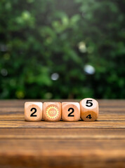 Poster - Happy new year 2025 with green business goal, Environmental sustainability concepts. Flipping 2024 to 2025 numbers with eco-friendly icon on wooden cube blocks on wood table, nature background.