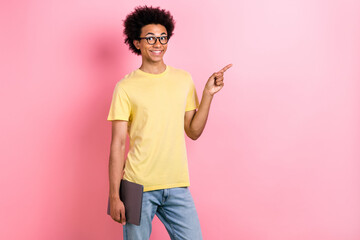 Wall Mural - Portrait of nice young man hold laptop direct finger empty space wear yellow t-shirt isolated on pink color background