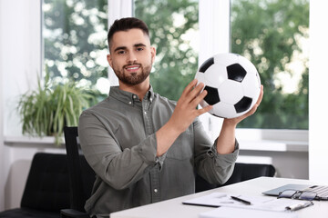 Canvas Print - Young man with soccer ball at table in office