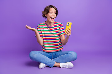 Sticker - Photo of positive glad funky girl wearing trendy striped clothes discussing news sitting floor isolated on violet color background