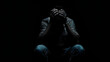 © Daniel - Man sitting alone felling sad worry or fear and hands up on head on black background