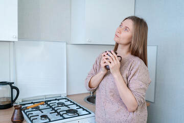 Wall Mural - A woman is standing in a kitchen with a cup in her hand