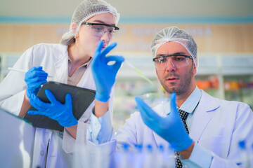 Wall Mural - scientists perform experiments and record data. people arranges equipment with test tubes and chemicals for producing medicine and biochemistry. man hold tubes of chemical liquids and plant samples.