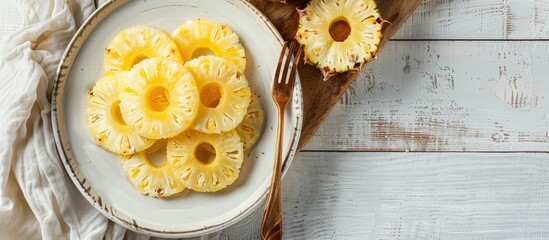 Sticker - Top view of a plate displaying canned pineapple rings accompanied by a fork, kitchen towel, on a white wooden table, with copy space image available.