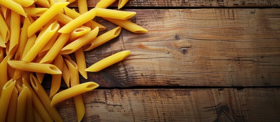 Poster - Close-up photo of vibrant uncooked penne pasta on a wooden table creates a textured Italian food background, perfect for text insertion in the image. Copy space image