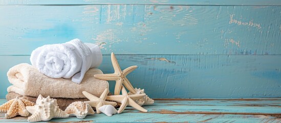 Aufkleber - Starfish-adorned towels displayed on a wooden surface with a light blue backdrop, offering ample copy space image.