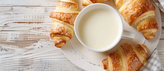 Poster - A cup of milk and crescent rolls displayed on a white wooden table, with a clear view from above, ideal for a copy space image.