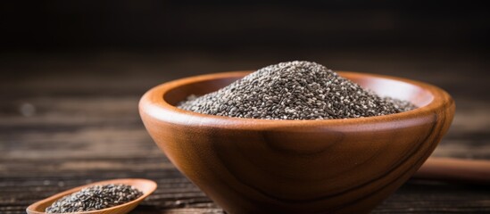 Poster - Close-up image featuring organic chia seeds in a wooden bowl, set against a dark wooden background with copy space.