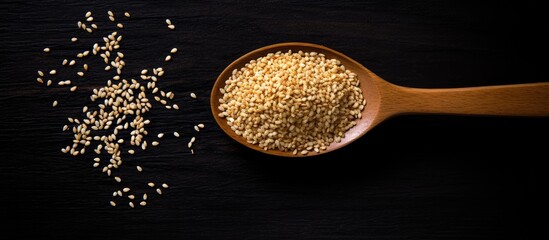 Poster - Toasted organic sesame seeds in a wooden spoon on a black background. Close-up, top view flat lay with a natural light setting, highlighting the seeds. Ideal for adding text with copy space image.