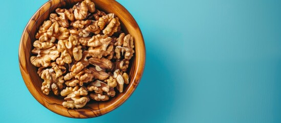 Poster - Close-up of walnut kernel halves in a wooden bowl on a colored background, emphasizing healthy eating and superfoods with a copy space image.