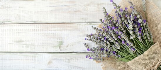 Poster - A dried lavender bouquet, gift-wrapped in textured green burlap, set on a white wooden background. Ideal for aromatherapy, organic home decor, spa, and Mother's Day, with room for copy space image.