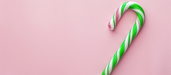 Poster - Green and white candy cane for Christmas displayed on a pink backdrop with ample copy space image available.