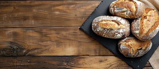 Poster - Fresh sourdough bread displayed on a black slate plate over a wooden table with copy space image.