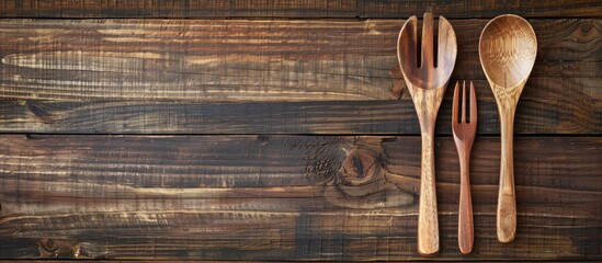 Aufkleber - Wooden spoon and fork displayed on a brown wooden background with copy space, viewed from above.