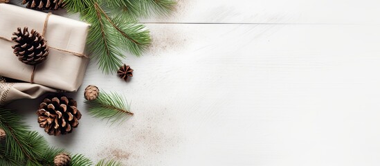 Poster - A festive Christmas arrangement with a gift, cozy blanket, pine cones, and evergreen branches on a rustic white backdrop. Flat lay design with room for text or images in the shot