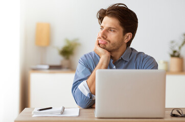 Aufkleber - A man sits at a desk with his hand on his chin, looking thoughtfully away from the laptop in front of him.