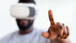 © Prostock-studio - A close-up photo shows African American man wearing a virtual reality headset, his right hand extended forward, with his index finger pointing up as he interacts with digital content.