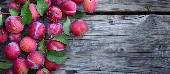 Poster - Abundance of copy space enhances the visual appeal of fresh pink plums with leaves on an aged wooden table, creating a rustic garden scene.