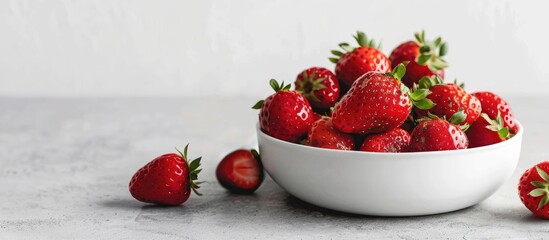 Poster - Fresh strawberries piled in a ceramic bowl on a rustic white surface with ample copy space image.