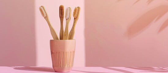 Poster - Eco-friendly bamboo toothbrushes displayed in a ceramic glass on a pink surface, emphasizing a zero-waste message with copy space image available.
