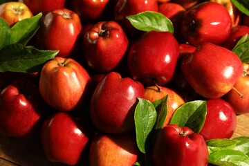 Wall Mural - Fresh ripe red apples and green leaves on wooden table, closeup