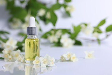 Wall Mural - Essential oil in bottle and beautiful jasmine flowers on white background