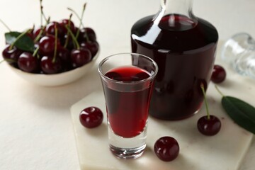 Canvas Print - Delicious cherry liqueur and berries on white table, closeup