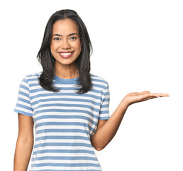 Wall Mural - young latina posing in studio showing a copy space on a palm and holding another hand on waist.