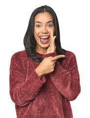 Wall Mural - simple portrait of a young latina saying a gossip, pointing to side reporting something.