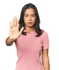 Wall Mural - simple portrait of a young latina standing with outstretched hand showing stop sign, preventing you.