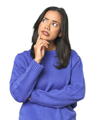 Wall Mural - simple portrait of a young latina looking sideways with doubtful and skeptical expression.