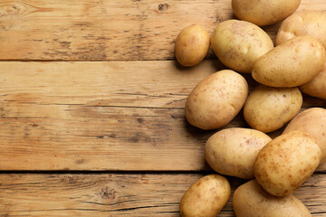 Canvas Print - Many fresh potatoes on wooden table, top view. Space for text