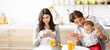 © Prostock-studio - A young family, a man, woman, and baby, are enjoying breakfast together in their kitchen. The woman is looking down at her phone while the man is interacting with the baby