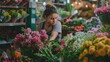 © Margo Alexa - young woman florist in flower shop. Surrounded by bright flowers and greenery, with ready-made bouquets on the shelves in the background.