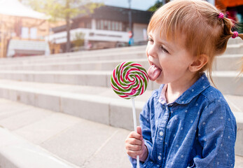 toddler girl eating big lollipop outdoors