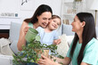 © Pixel-Shot - Young lesbian couple with adopted little girl watering plant at home