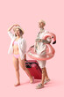 © Pixel-Shot - Young couple with suitcase and inflatable ring on pink background