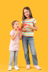 Poster - Happy little girls with slices of fresh watermelon on yellow background