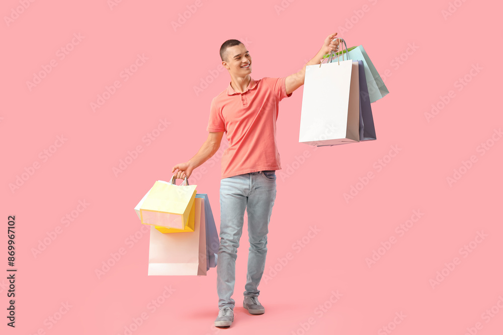 Young man with shopping bags on pink background