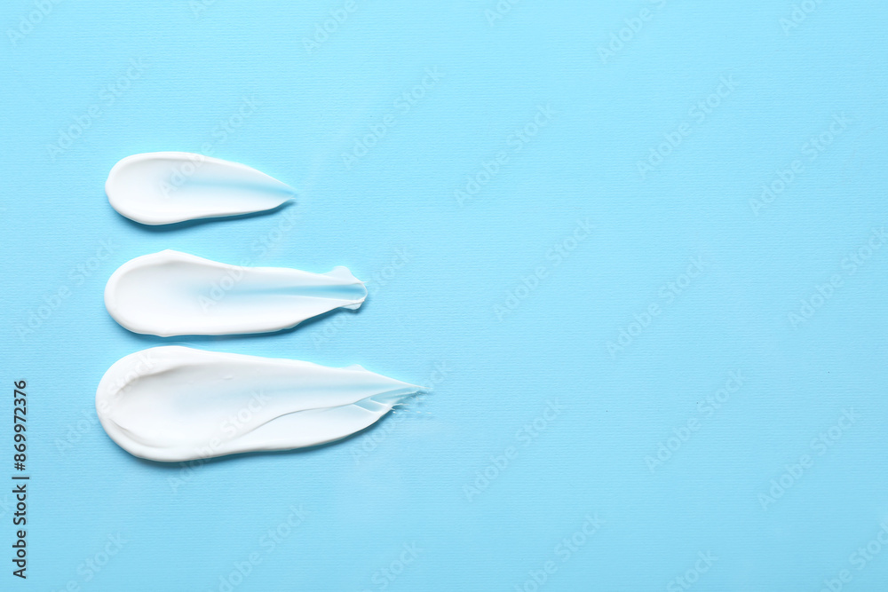 Samples of cosmetic cream on blue background