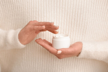 Beautiful young woman with jar of cream, closeup