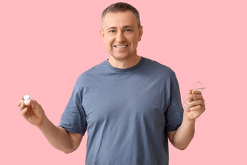 Wall Mural - Happy mature man with contact lens case and eyeglasses on pink background