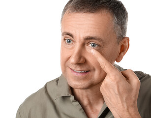 Wall Mural - Mature man putting in contact lenses on white background