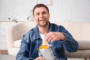 Poster - Handsome happy young man with tasty potato chips at home