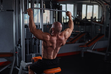 Wall Mural - Caucasian man doing lat pull-downs on a machine. 