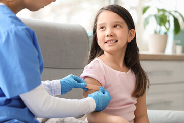 Canvas Print - Little Asian girl applying medical patch after vaccination in clinic