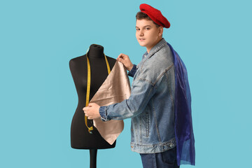 Wall Mural - Teenage fashion designer with cloth and mannequin on blue background